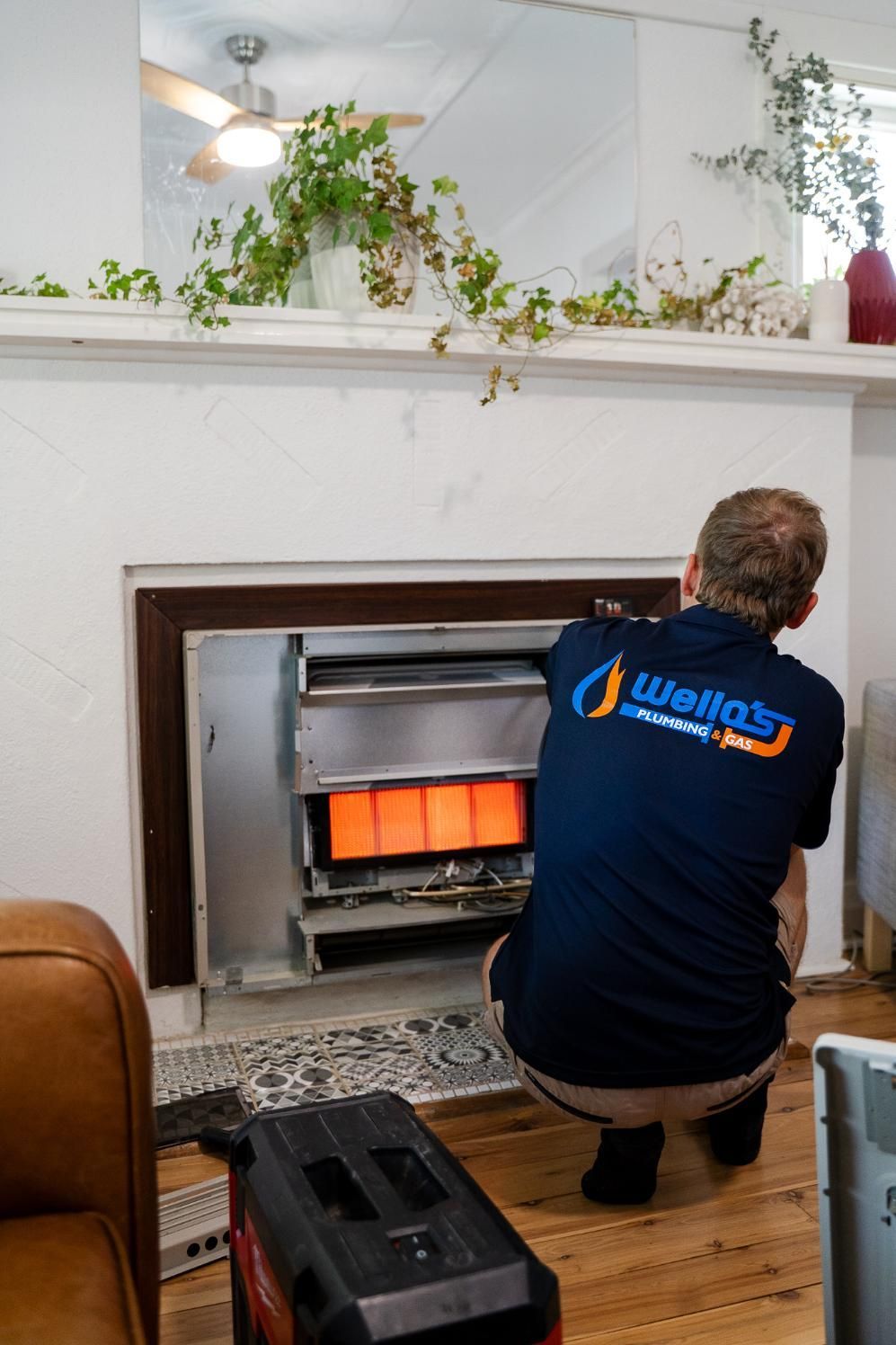 A Man is Working on a Fireplace in a Living Room — Wello's Plumbing & Gas In Thurgoona, NSW