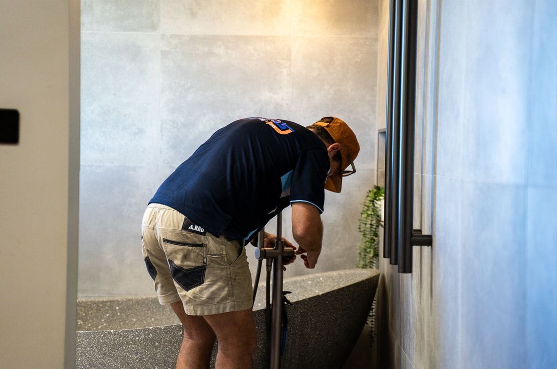 A Man is Working on a Bathtub in a Bathroom — Wello's Plumbing & Gas In Thurgoona, NSW