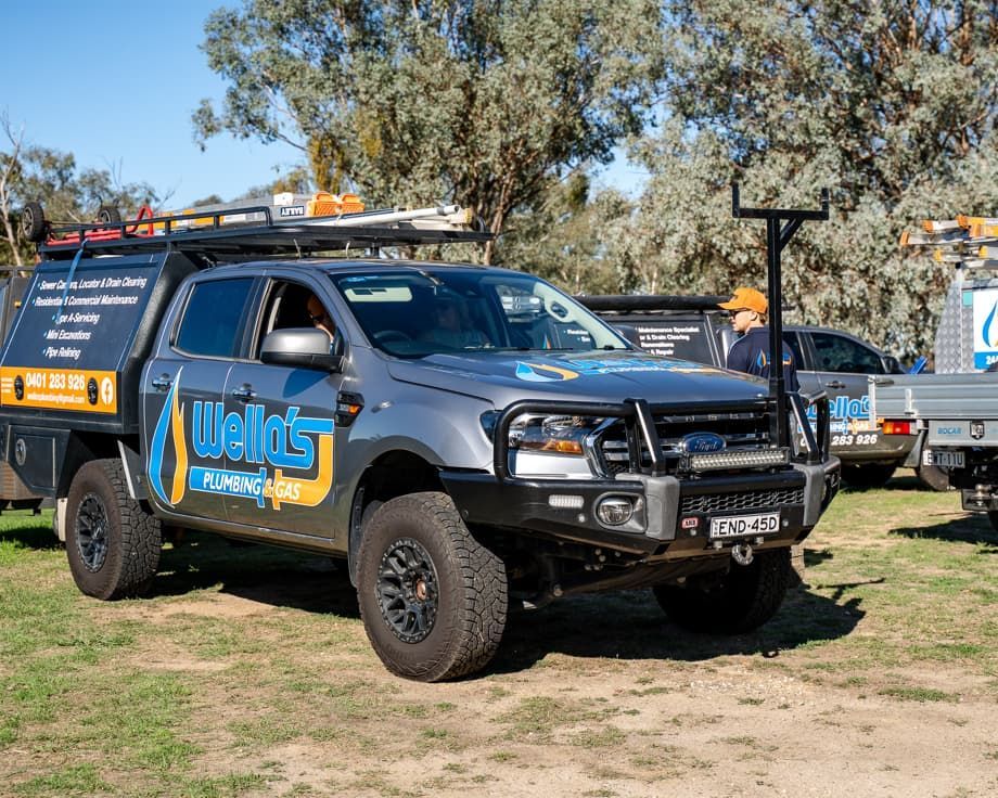 A Gray Truck is Parked in a Grassy Field — Wello's Plumbing & Gas In Thurgoona, NSW
