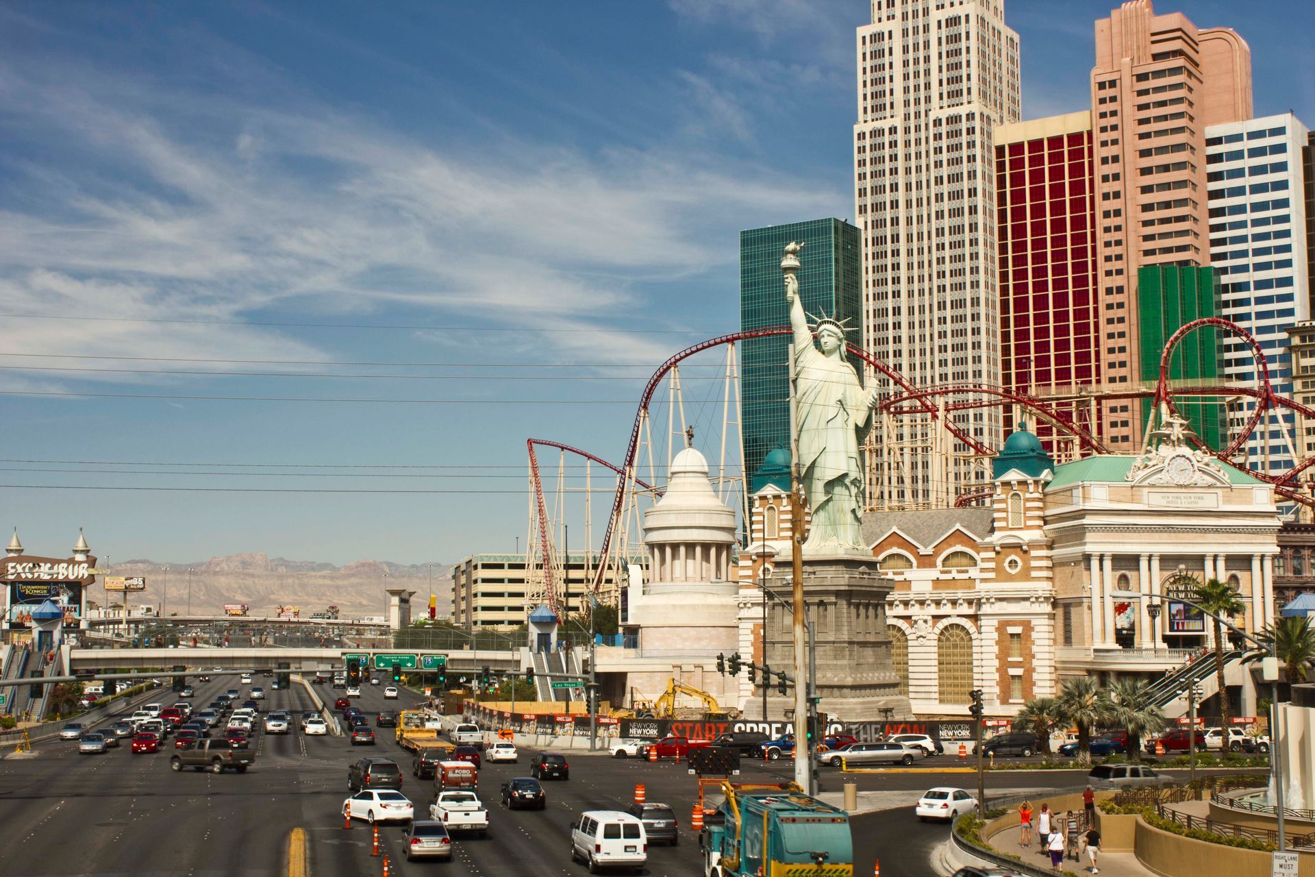 Hotel and Casino in Las Vegas with Statue of Liberty, roller coaster, and traffic on a sunny day.