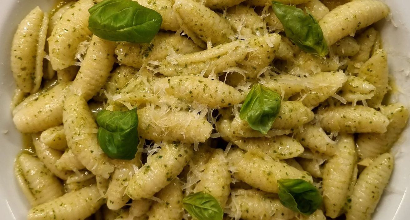 Un primer plano de un plato de pasta con albahaca y queso.