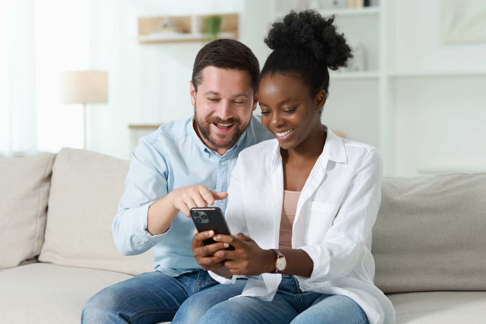 Woman kisses older woman on the cheek. Both smile. One wears orange, the other a blue sweater. White background.