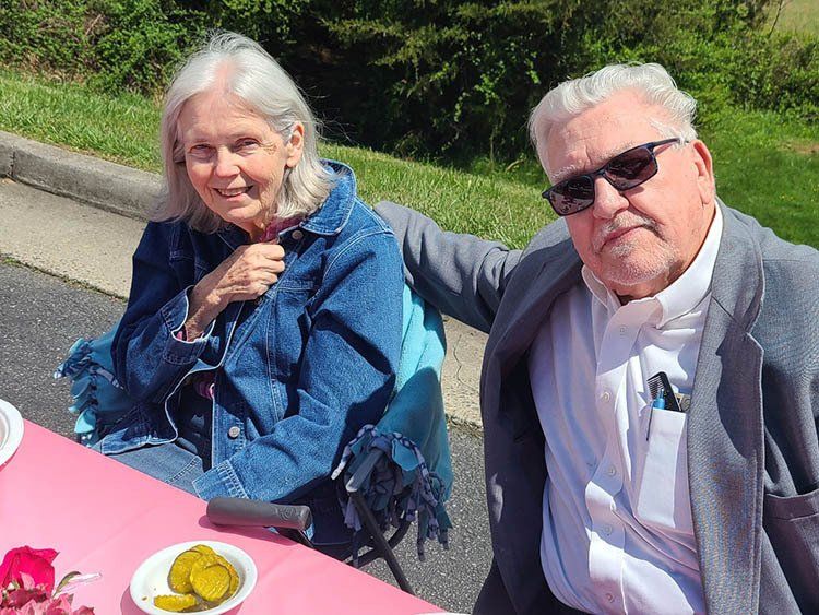 A man and a woman are sitting at a table with pickles on it.