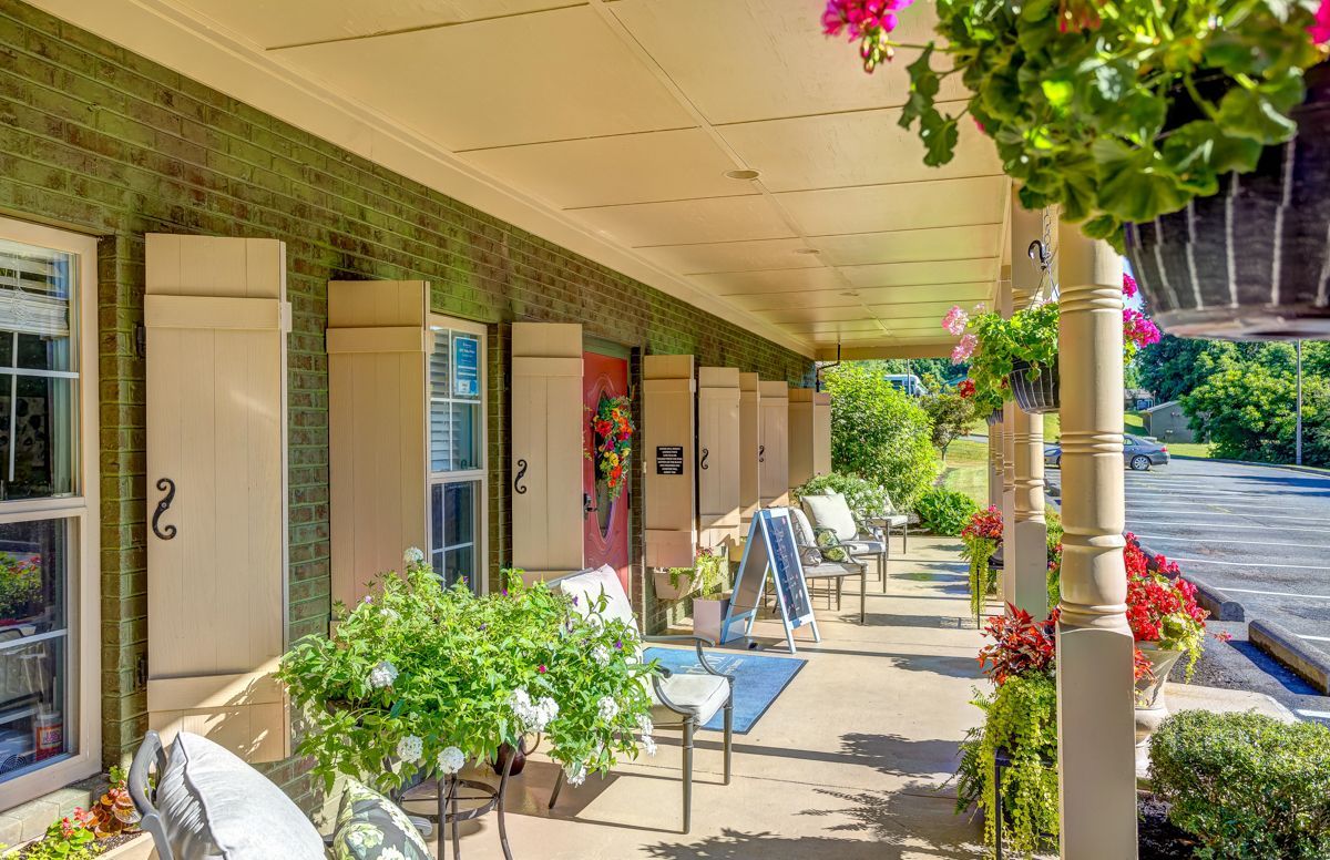 There is a porch with chairs and flowers on it.