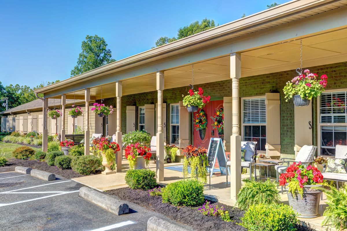 A row of houses with a porch and flowers in front of them.