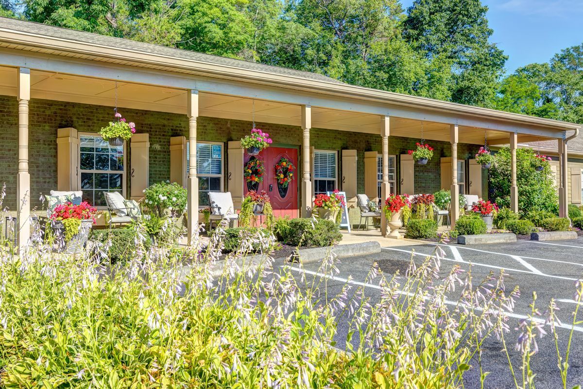A large house with a porch and a parking lot in front of it.