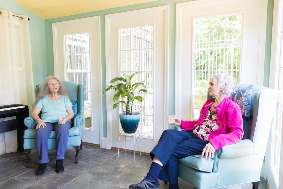 Two elderly women are sitting in chairs in a living room.