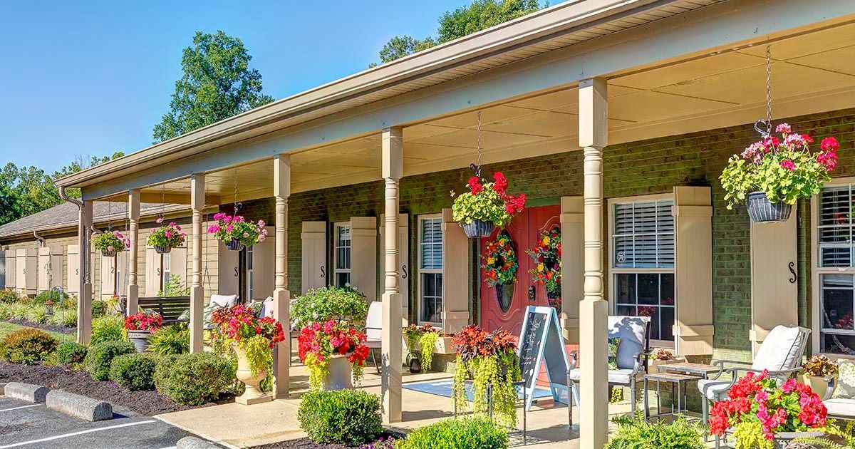 A row of houses with a porch covered in flowers and chairs.