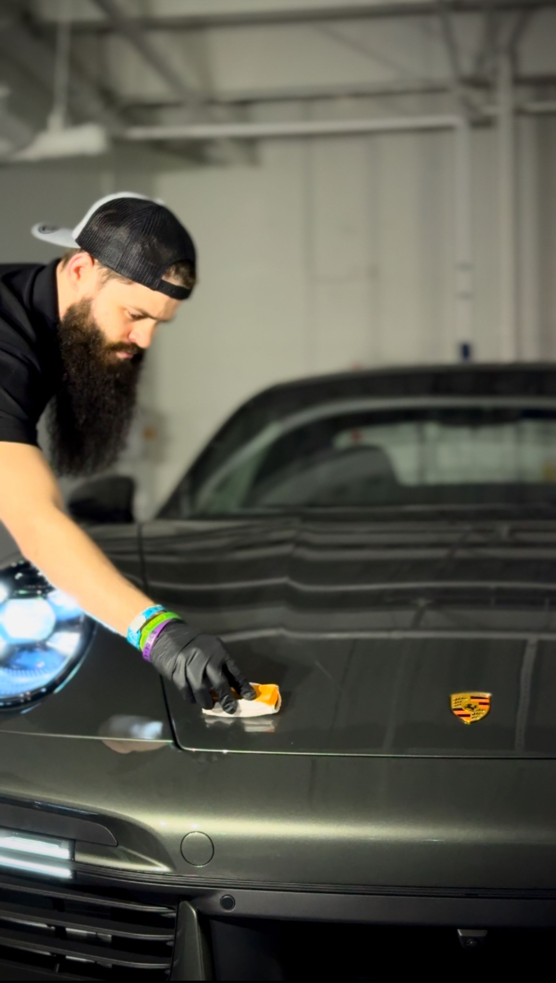 A man with a beard is polishing the hood of a car.