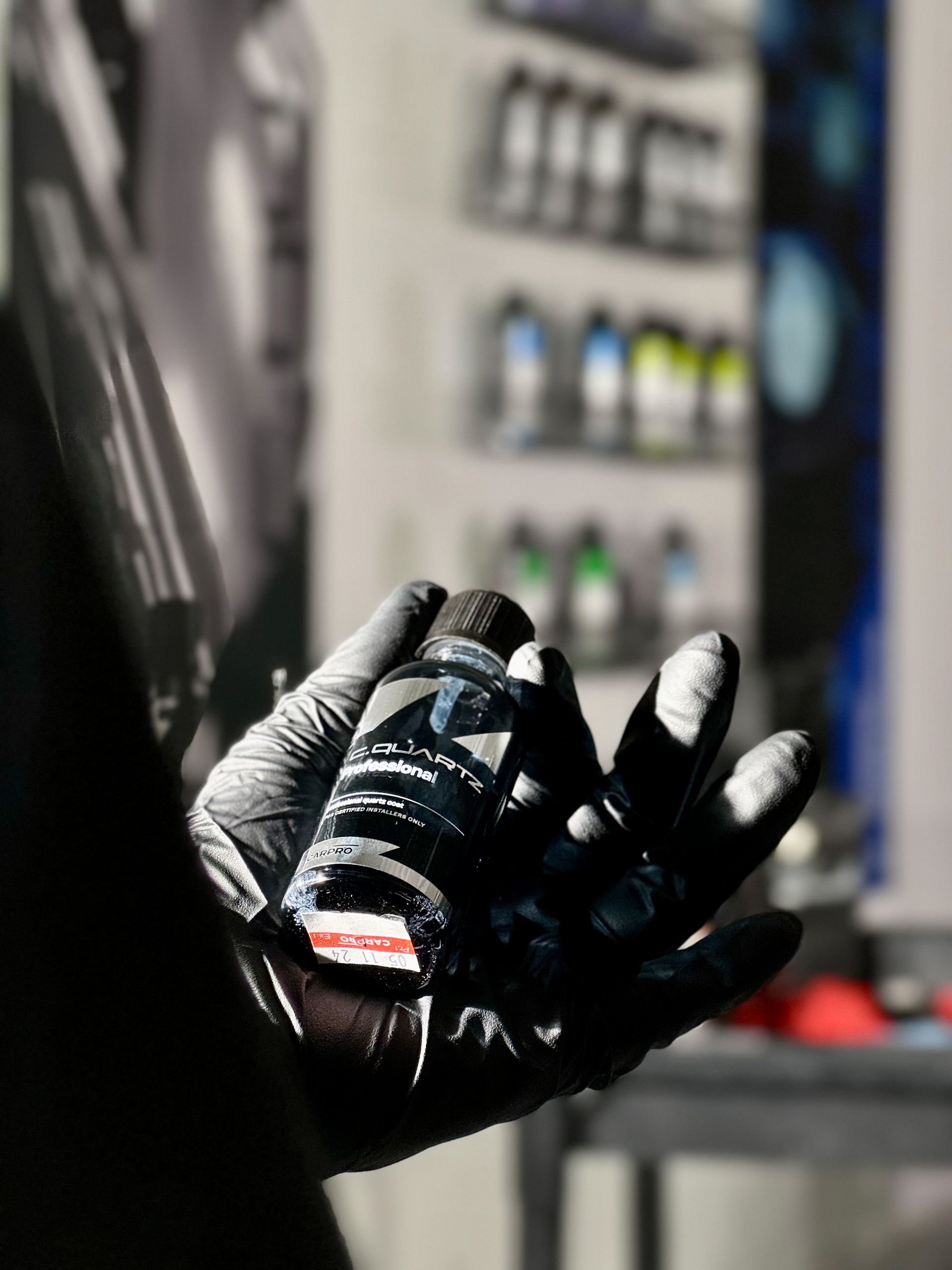 A person wearing gloves is holding a small bottle in their hand.