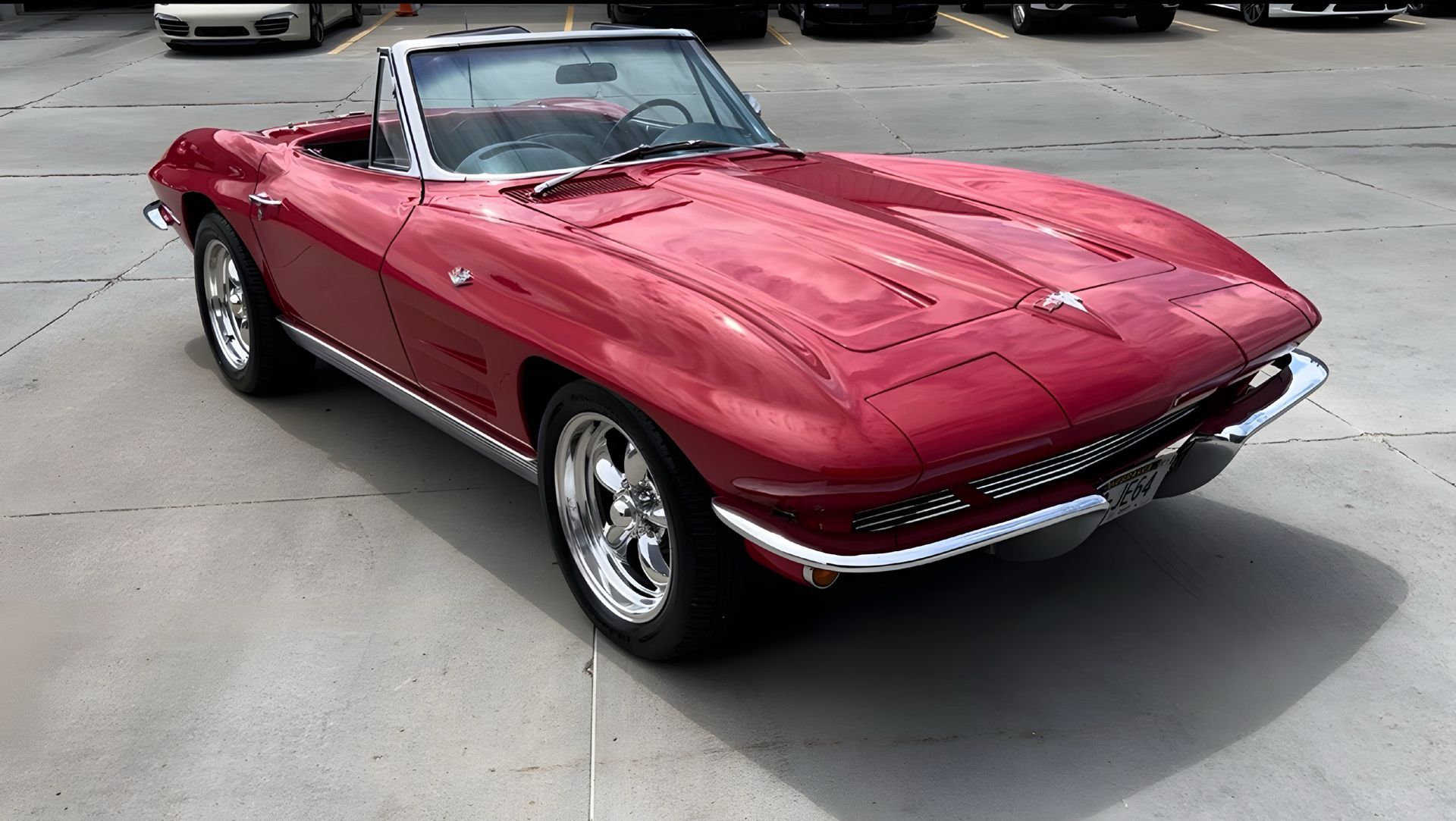 A red corvette convertible is parked in a parking lot.