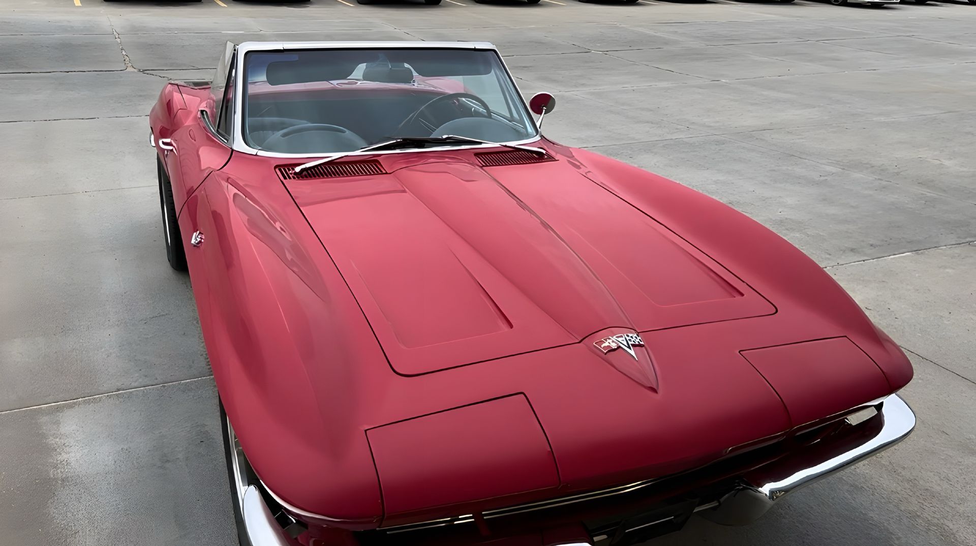 A red corvette convertible is parked in a parking lot.