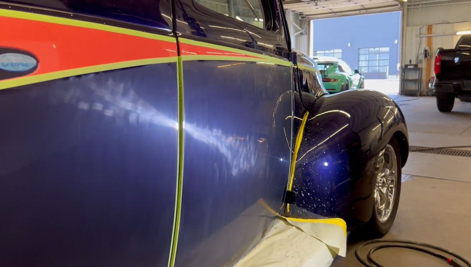 A blue car is sitting in a garage with yellow tape on it.