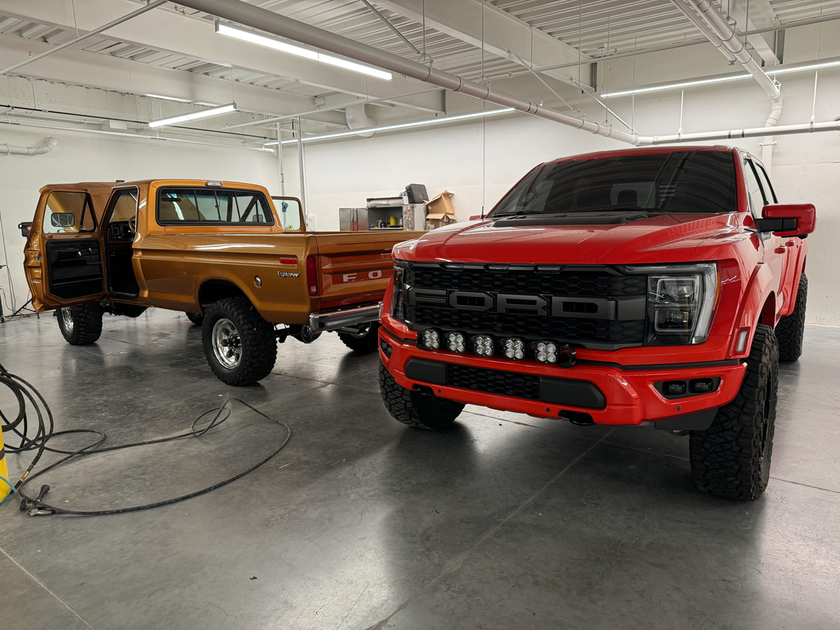 Two ford trucks are parked next to each other in a garage.