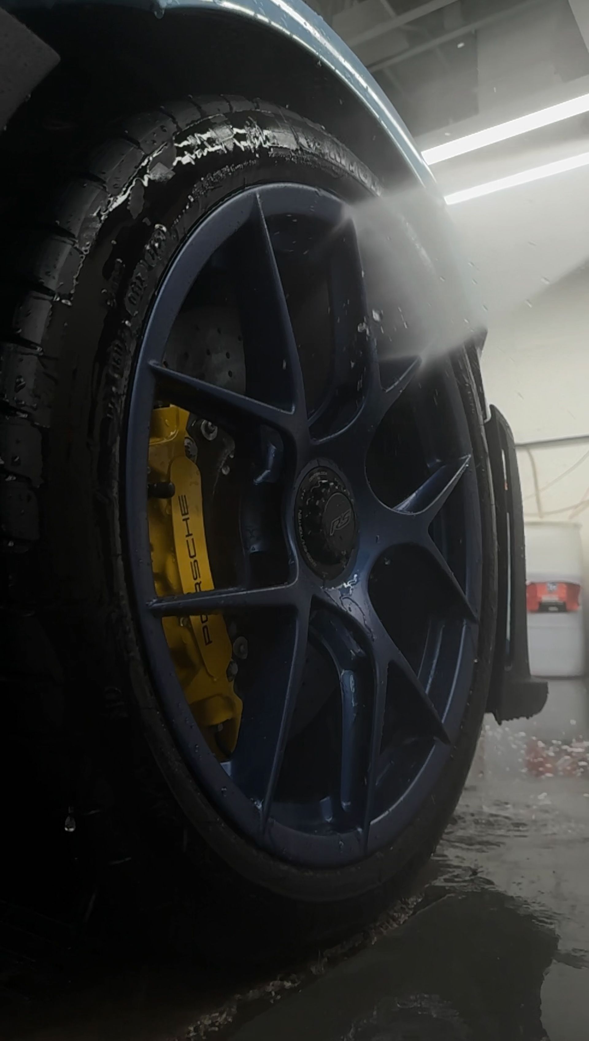 A close up of a car wheel being washed in a garage.