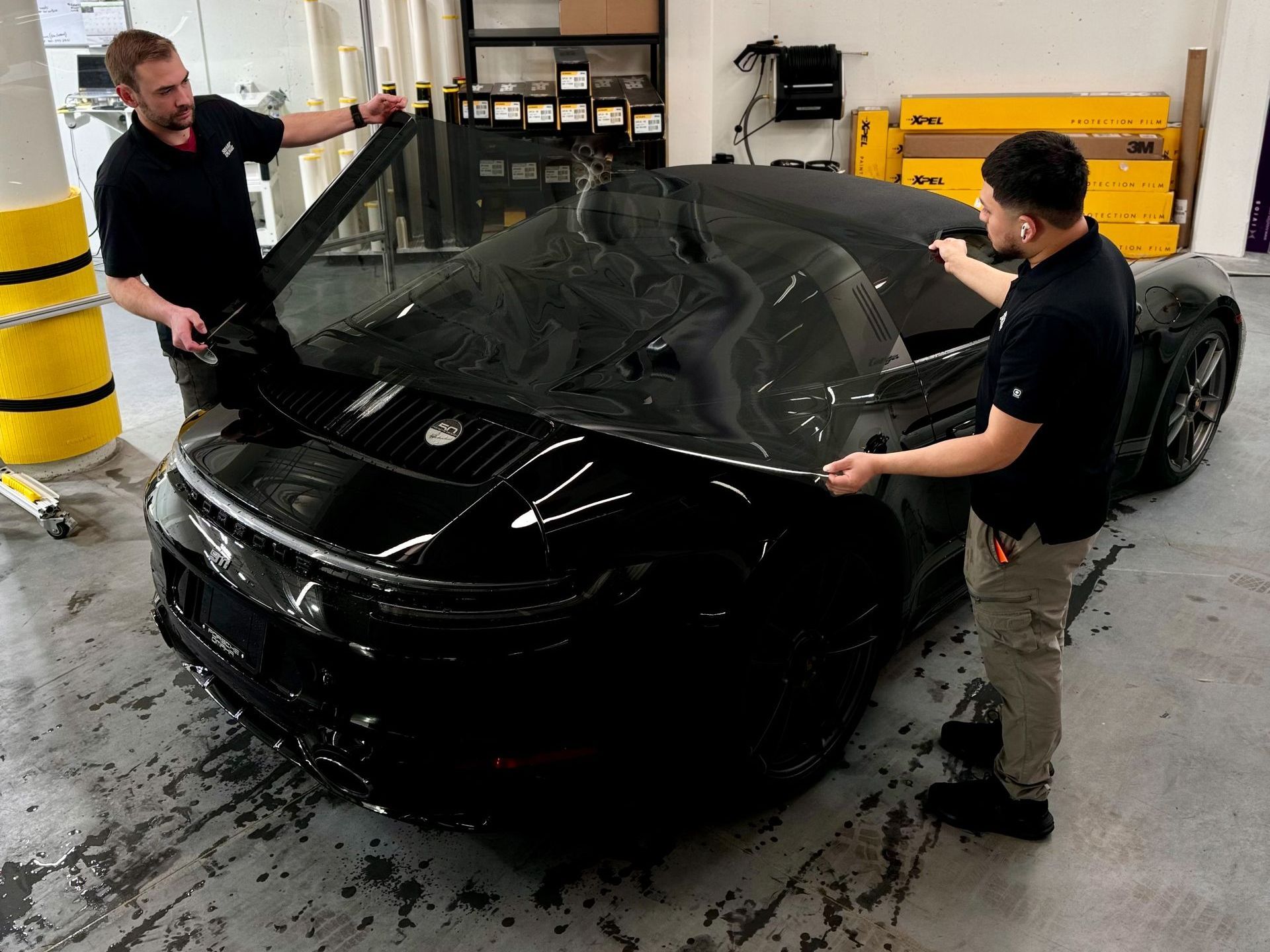 A group of people are working on a car in a garage.
