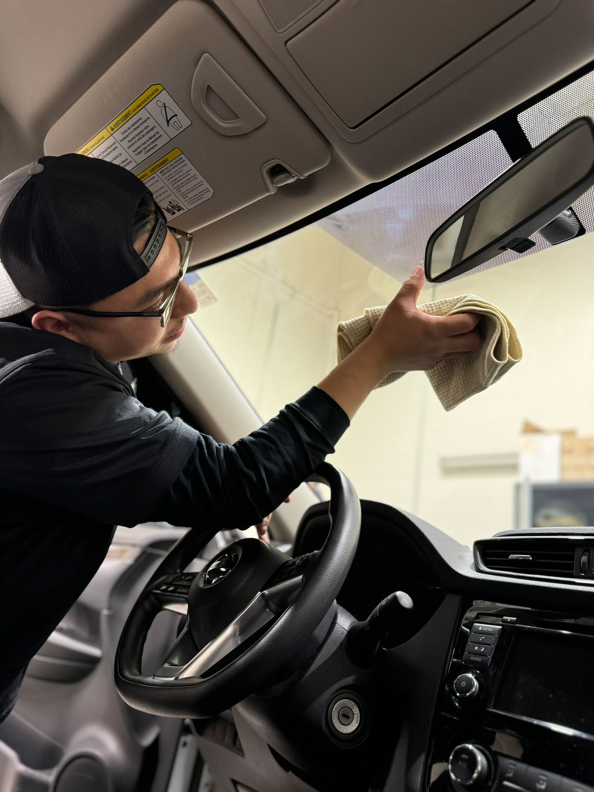 A man with a beard is polishing the hood of a car.