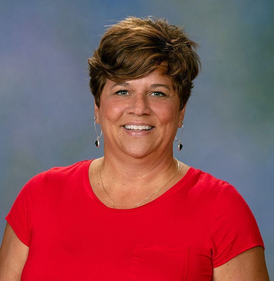 A woman in a red shirt is smiling for the camera