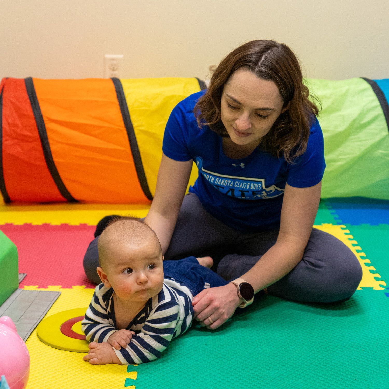 A woman is sitting on the floor playing with a baby.