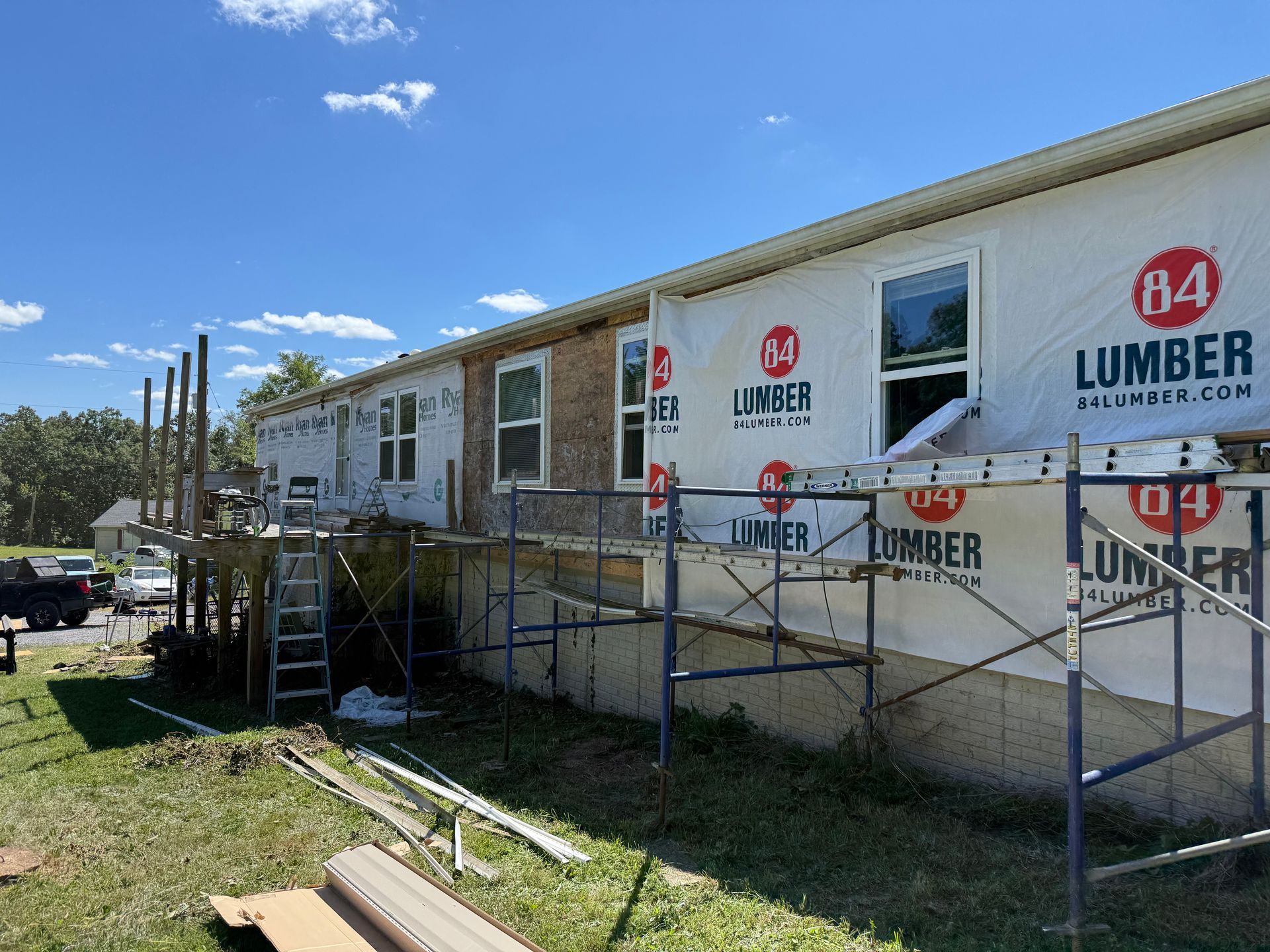 Construction in progress: house exterior with scaffolding, partially covered with paper and windows.