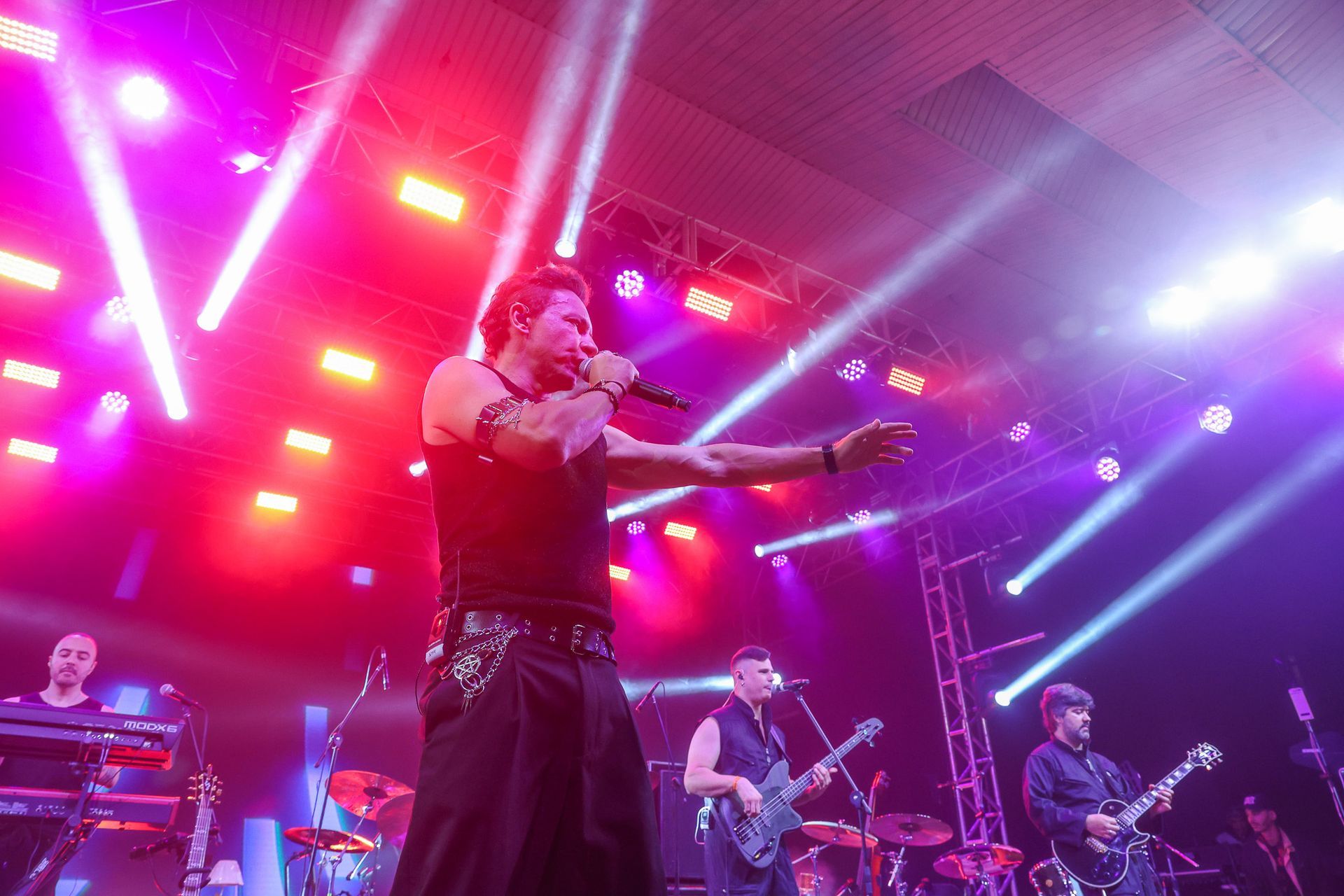 Uma banda se apresenta, com o vocalista principal estendendo a mão para o público.