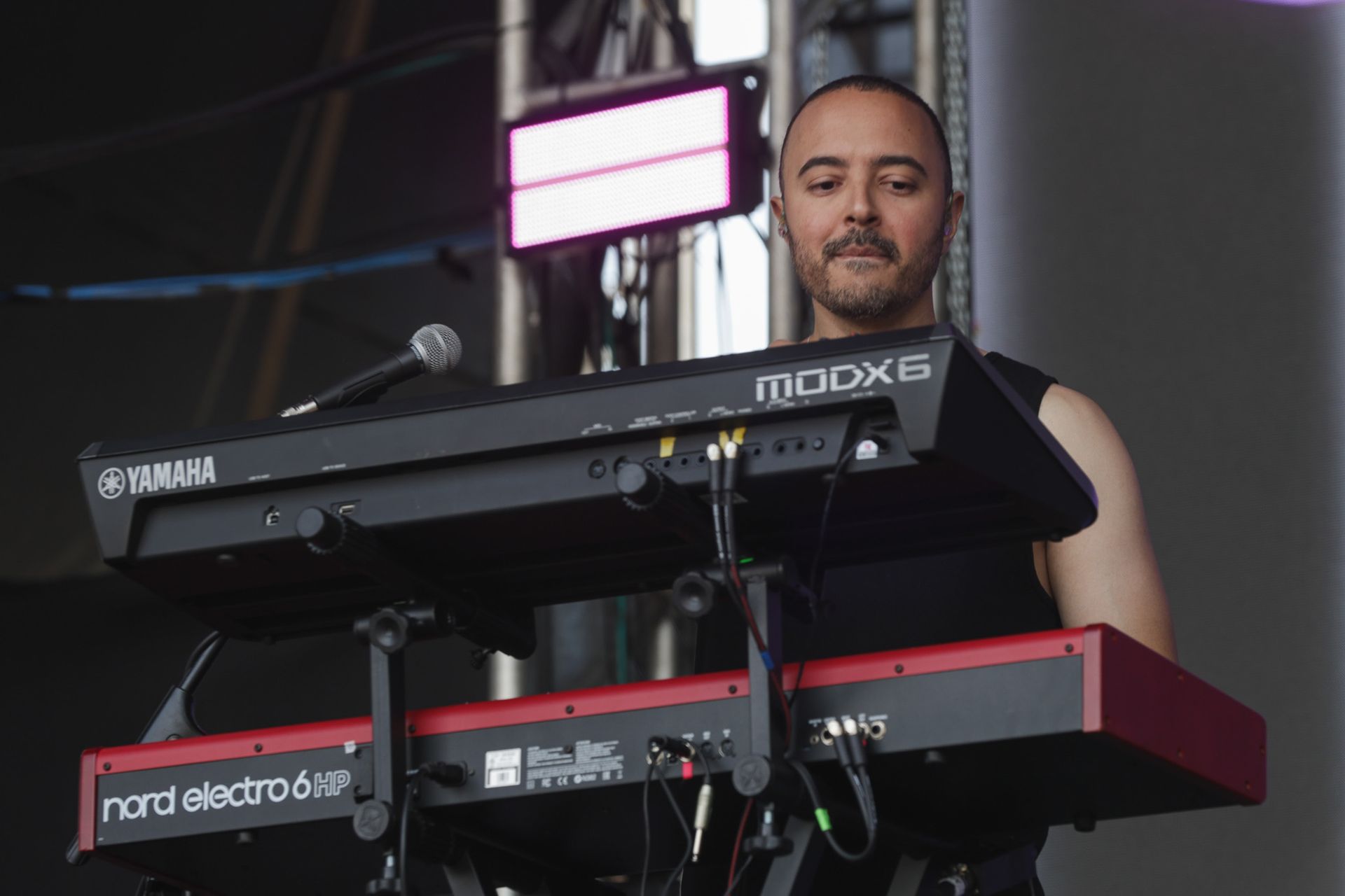 Um músico está em pé atrás de um teclado de dois níveis durante uma apresentação.
