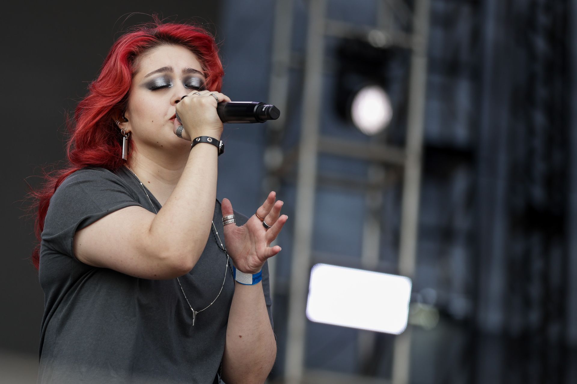Uma cantora com vibrantes cabelos se apresenta no palco, de olhos fechados e segurando um microfone.