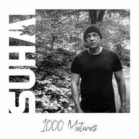 Homem de camiseta preta e gorro em pé em frente a uma folhagem. Capa do álbum 