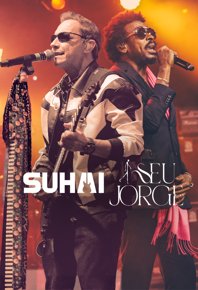 Suhai e Seu Jorge se apresentam no palco, com iluminação cênica em tons de laranja e amarelo.
