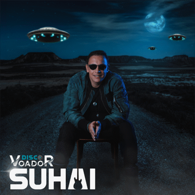 Homem de óculos escuros sentado em uma cadeira em uma estrada com OVNIs no céu noturno. O texto diz 