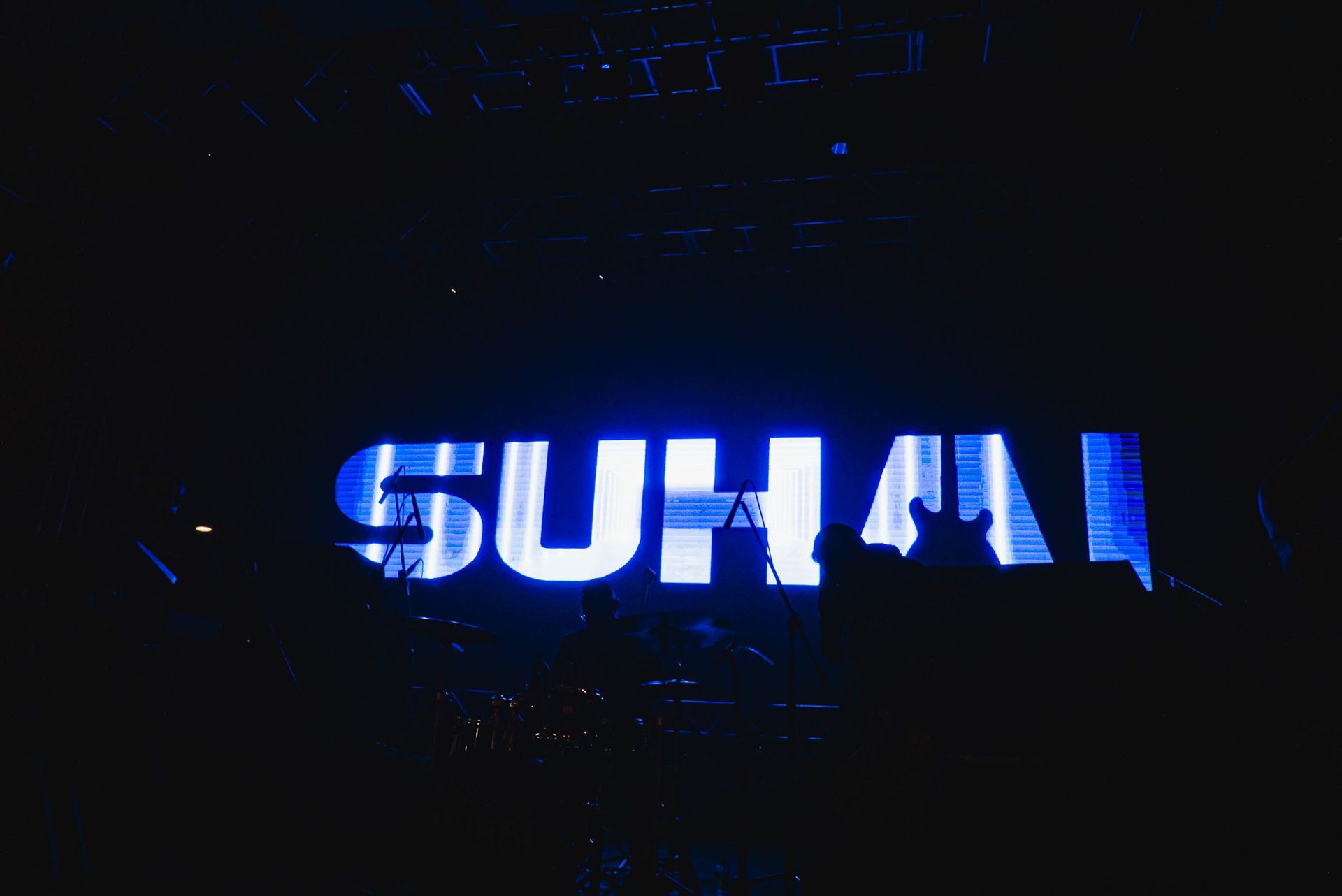 Uma casa de shows escura com um grande letreiro azul brilhante com a inscrição 