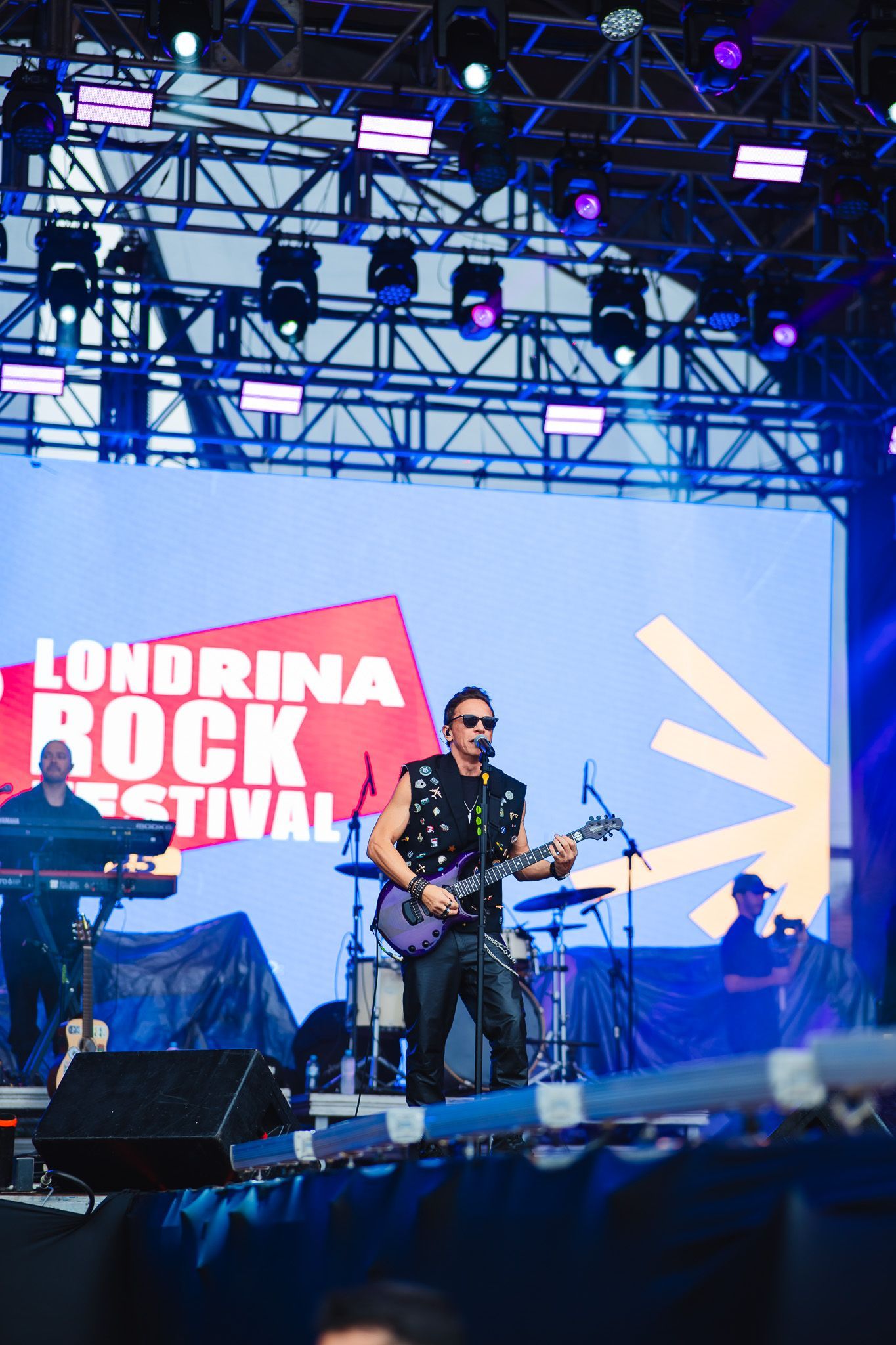 Um músico se apresenta no palco do Londrina Rock Festival, tocando uma guitarra roxa.