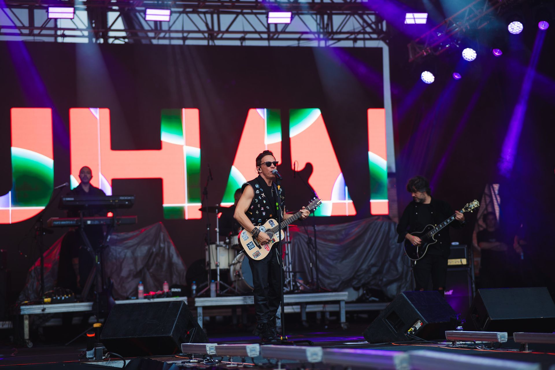 Banda se apresentando no palco com um telão exibindo o nome 