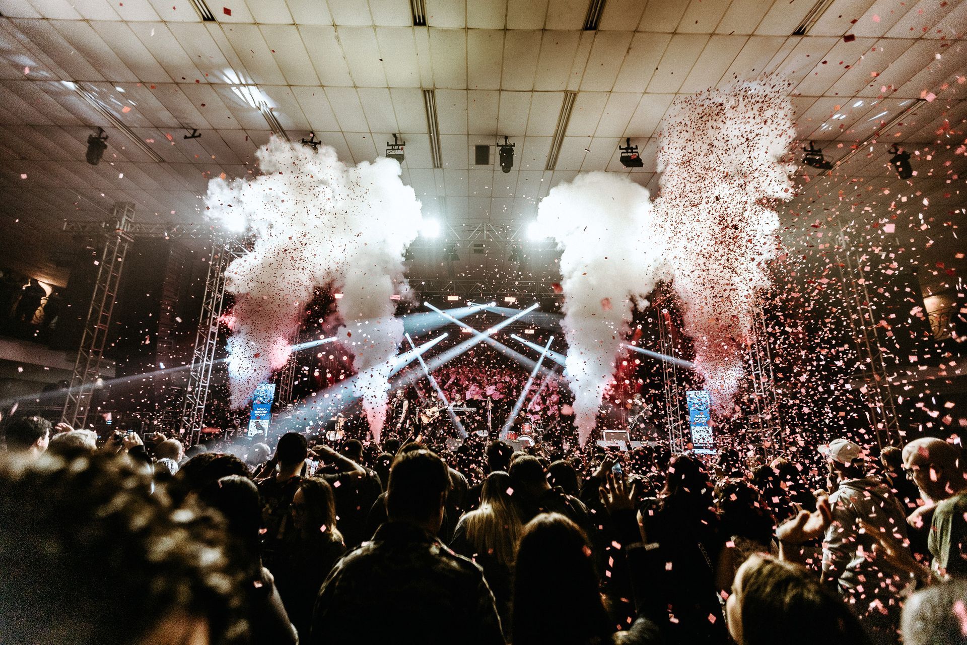 Concerto com chuva de confetes e luzes do palco iluminando a multidão.