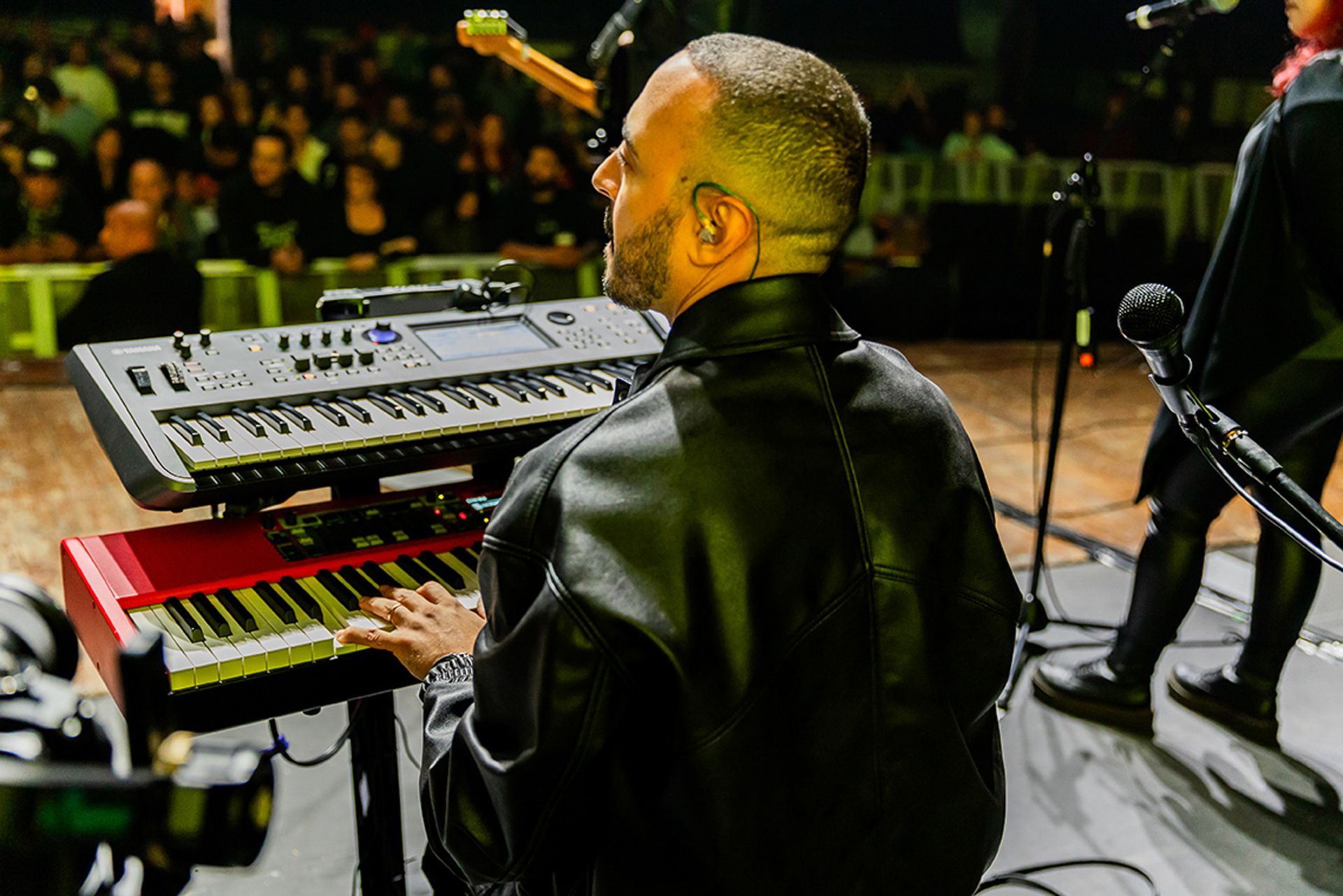 Um músico toca teclado no palco diante de uma plateia ao vivo.