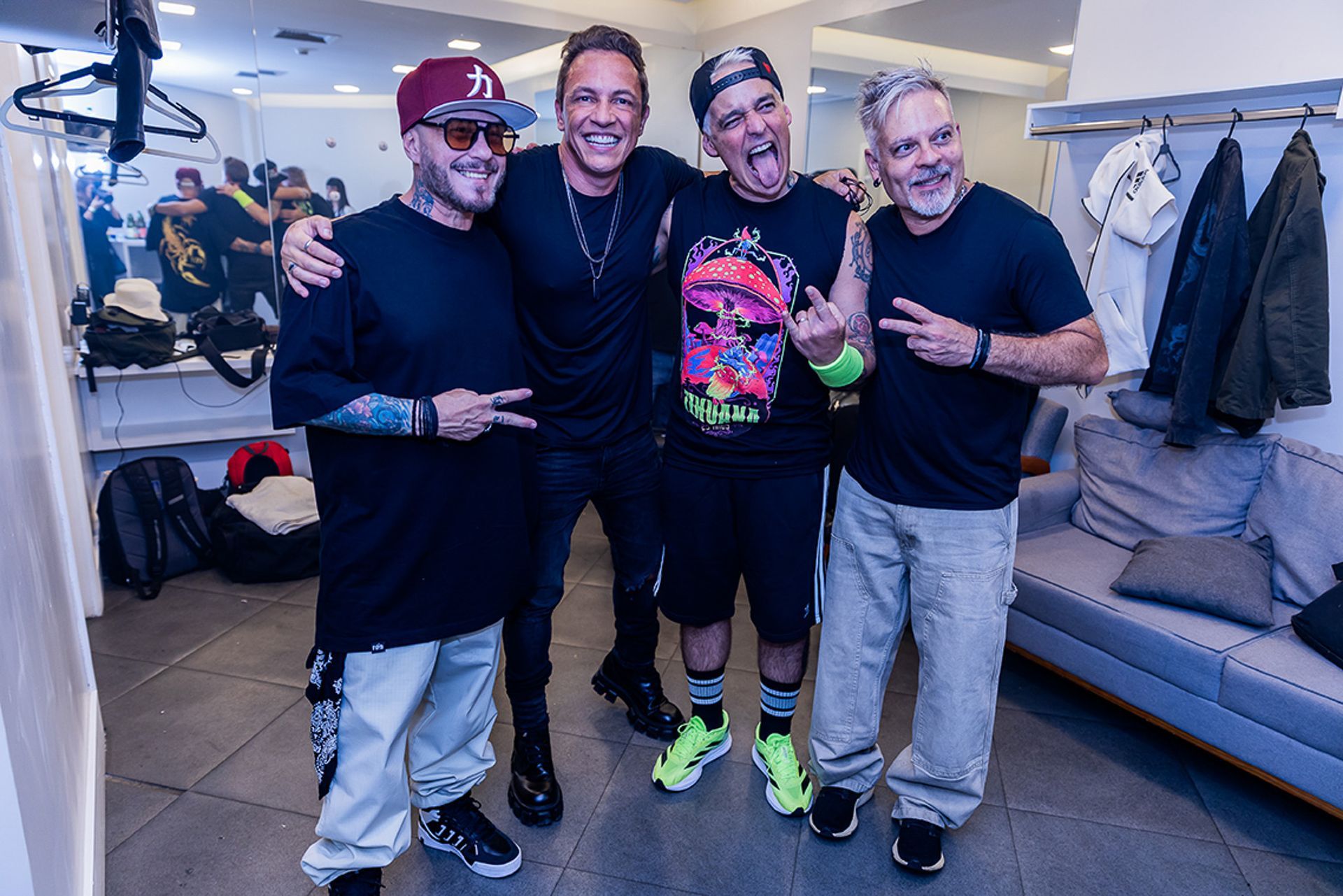 Quatro pessoas em pé juntas em uma sala, sorrindo e posando para uma foto em um ambiente interno informal.