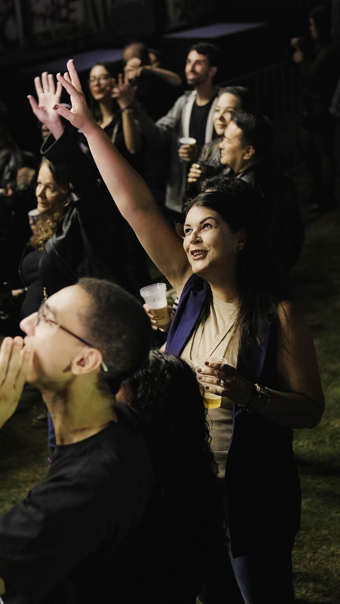 Pessoas em um local escuro olhando para cima com entusiasmo, uma pessoa em primeiro plano estendendo a mão em direção à luz.