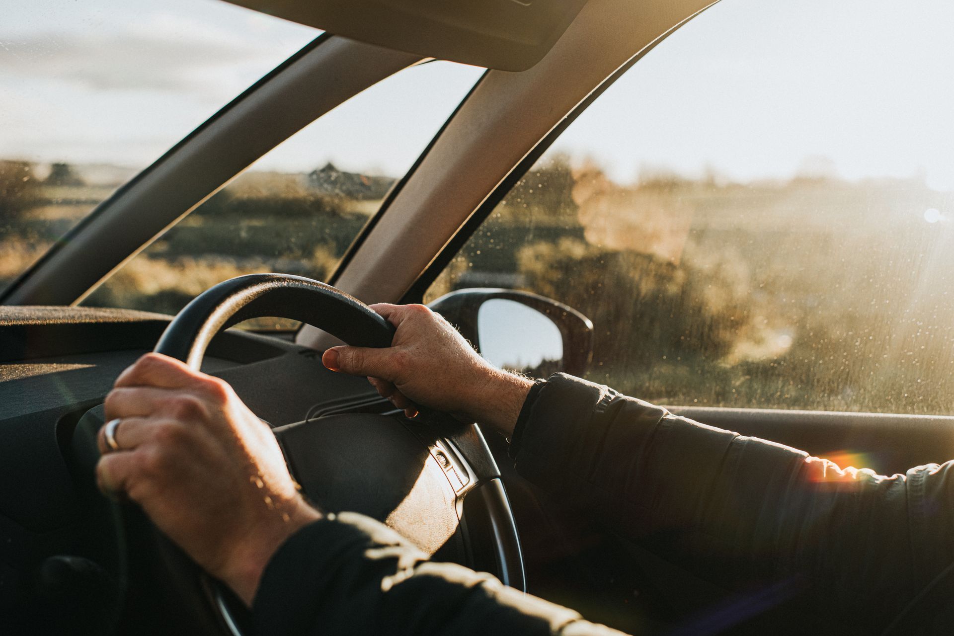 Hand holds a black steering wheel.