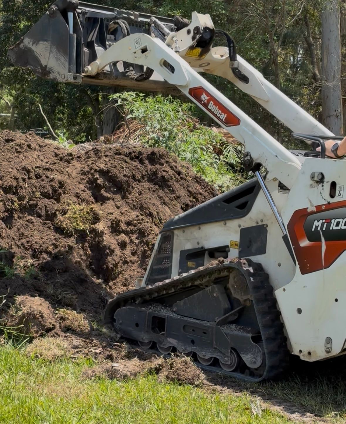 White Bobcat Track Loader Moving a Pile of Dirt — Borehams Hire In Meridan Plains, QLD