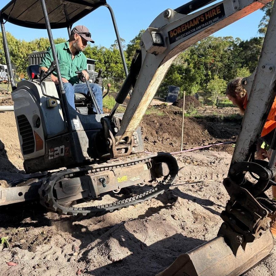 Man Operating an Excavator in a Sandy Area; Another Person Near the Machine — Borehams Hire In Meridan Plains, QLD