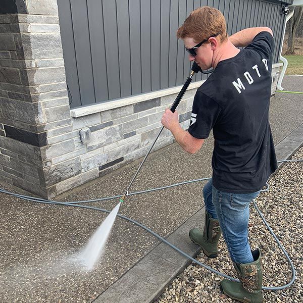 Man Pressure Washing Concrete Pathway  — Woodstock, ON — Exterior Kleen