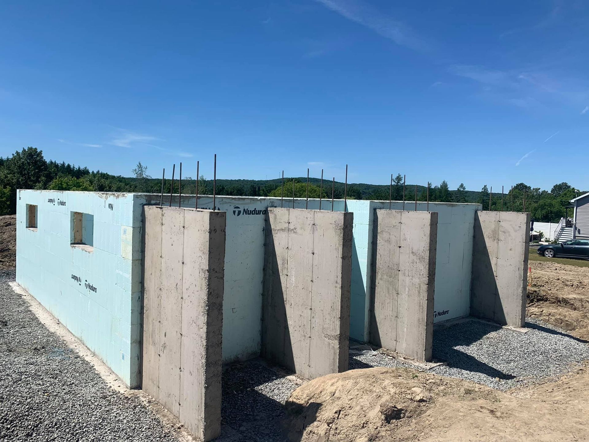 Fondation en béton et mousse bleue en construction à l'extérieur par une journée ensoleillée.