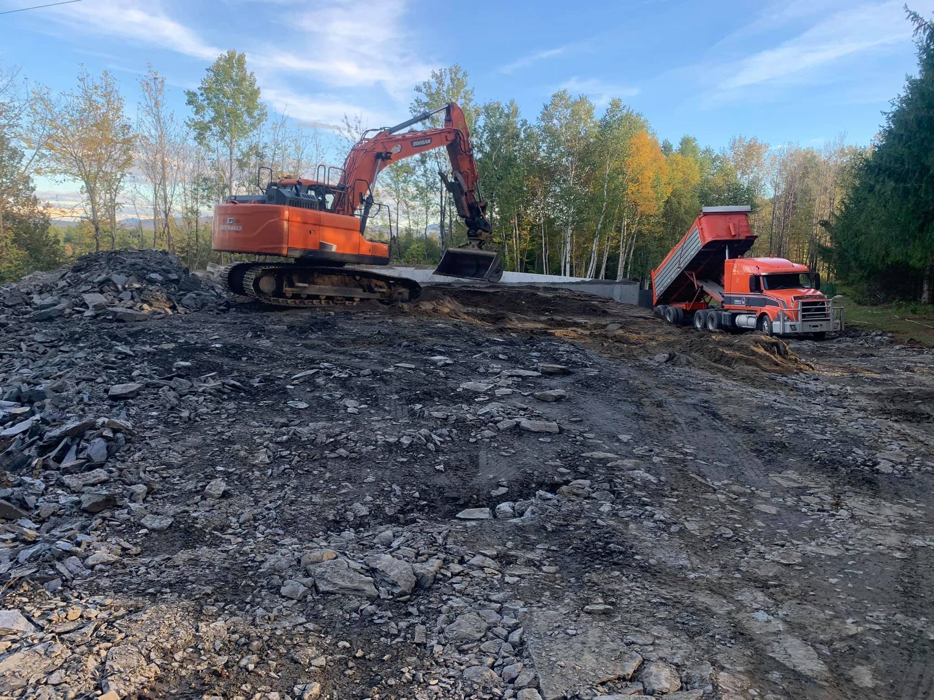 Une excavatrice charge de la terre dans un camion à benne basculante sur un chantier de construction.