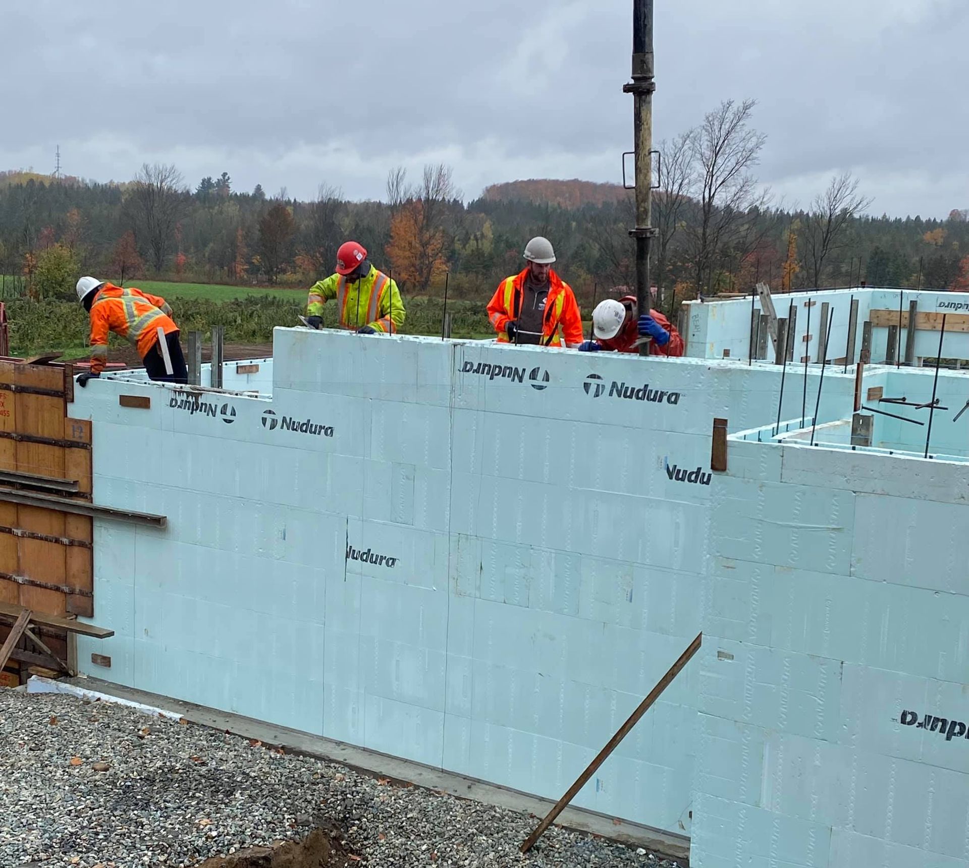 Des ouvriers du bâtiment coulent du béton dans des coffrages en béton isolés pour les fondations d'un bâtiment à l'extérieur.