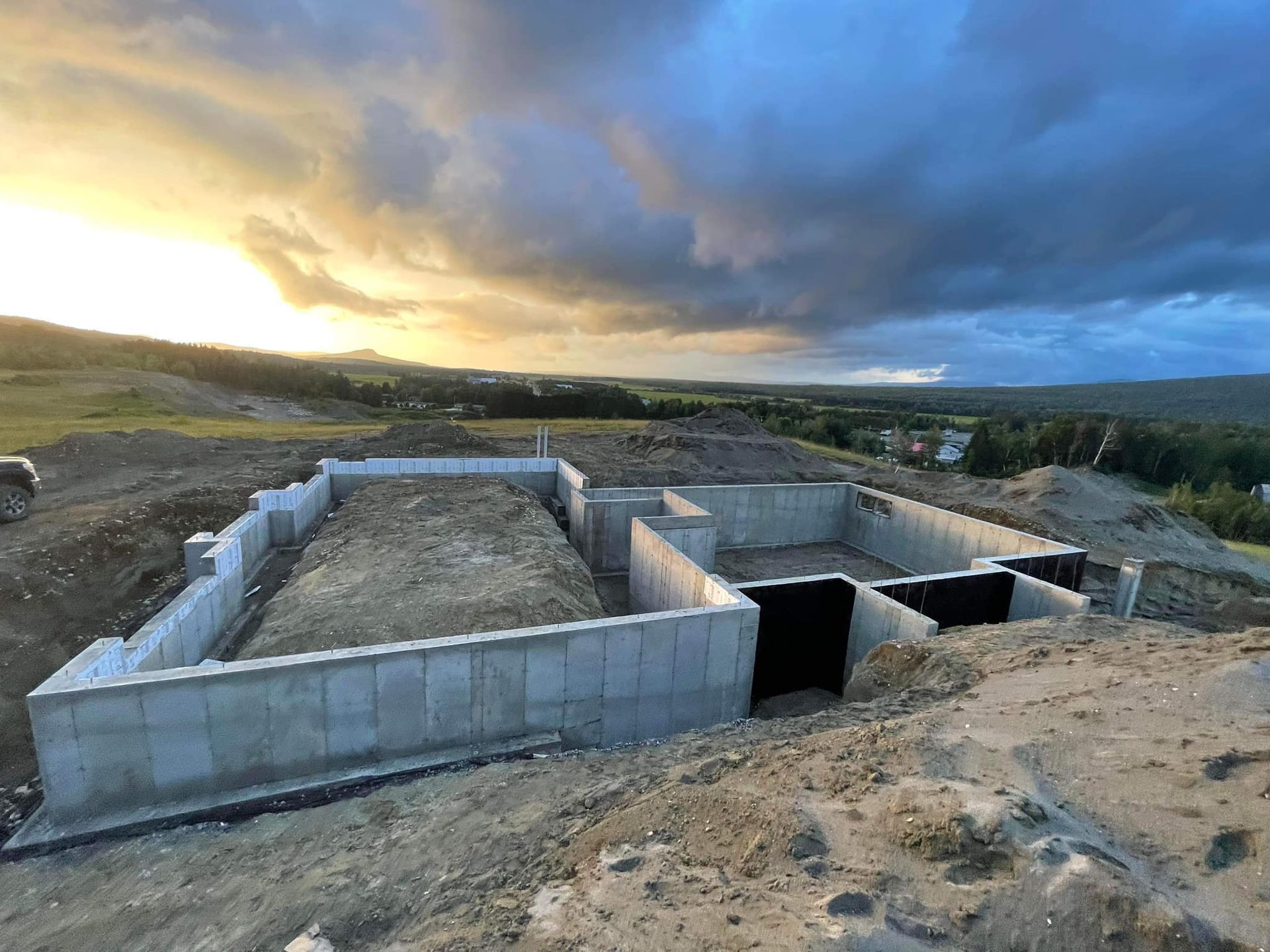 Fondation en béton d'une maison en construction sur une colline au coucher du soleil.