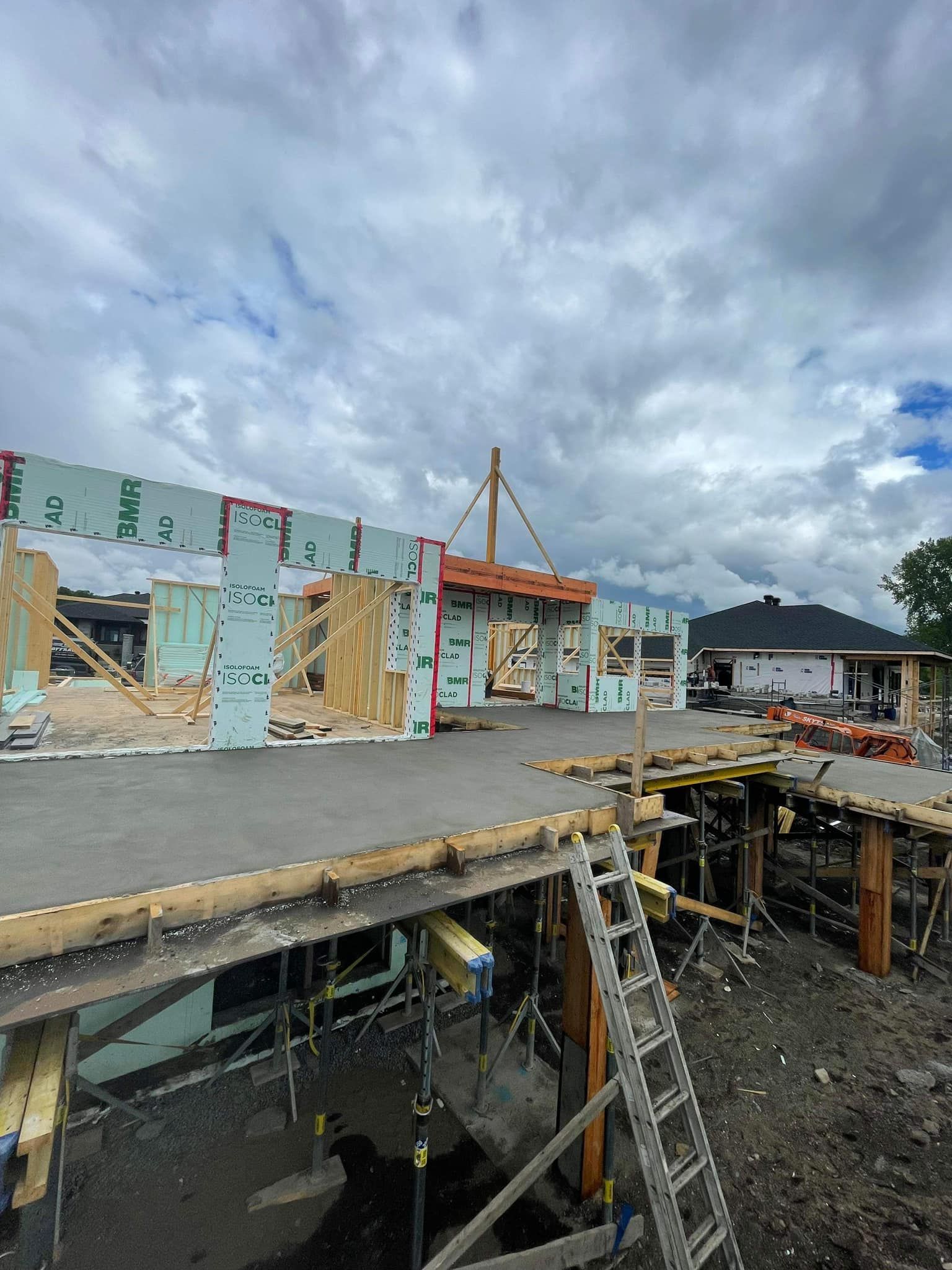 Chantier de construction avec un bâtiment en cours de construction sous un ciel nuageux.