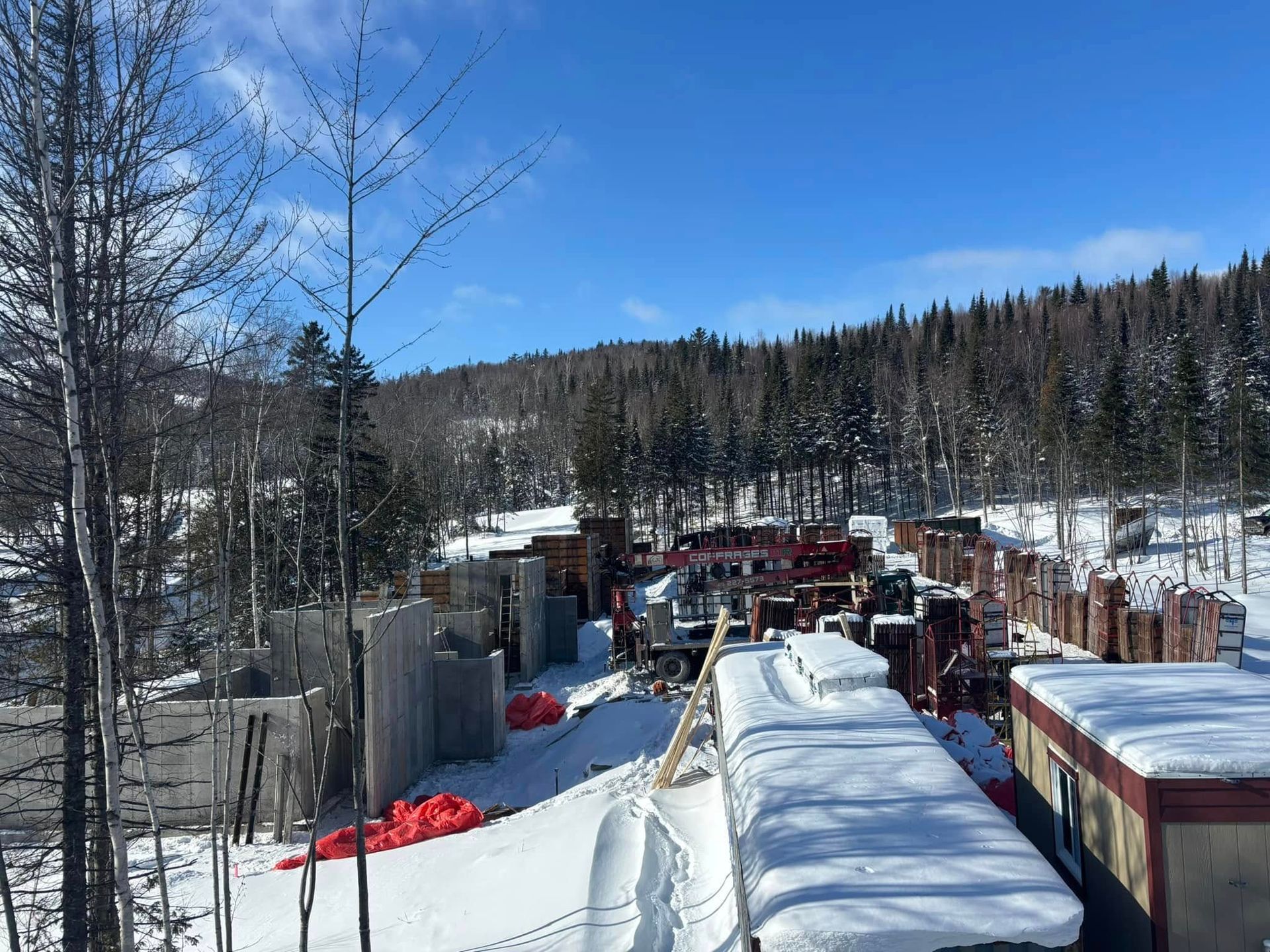Matériaux de construction dans un paysage enneigé avec des arbres et un ciel bleu.
