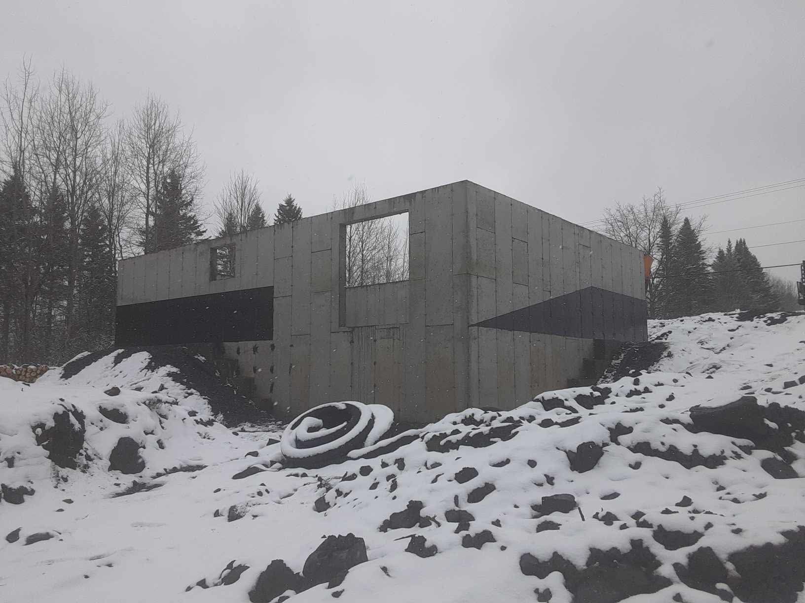 Fondation en béton d'un bâtiment avec des ouvertures de fenêtres dans un environnement extérieur enneigé.