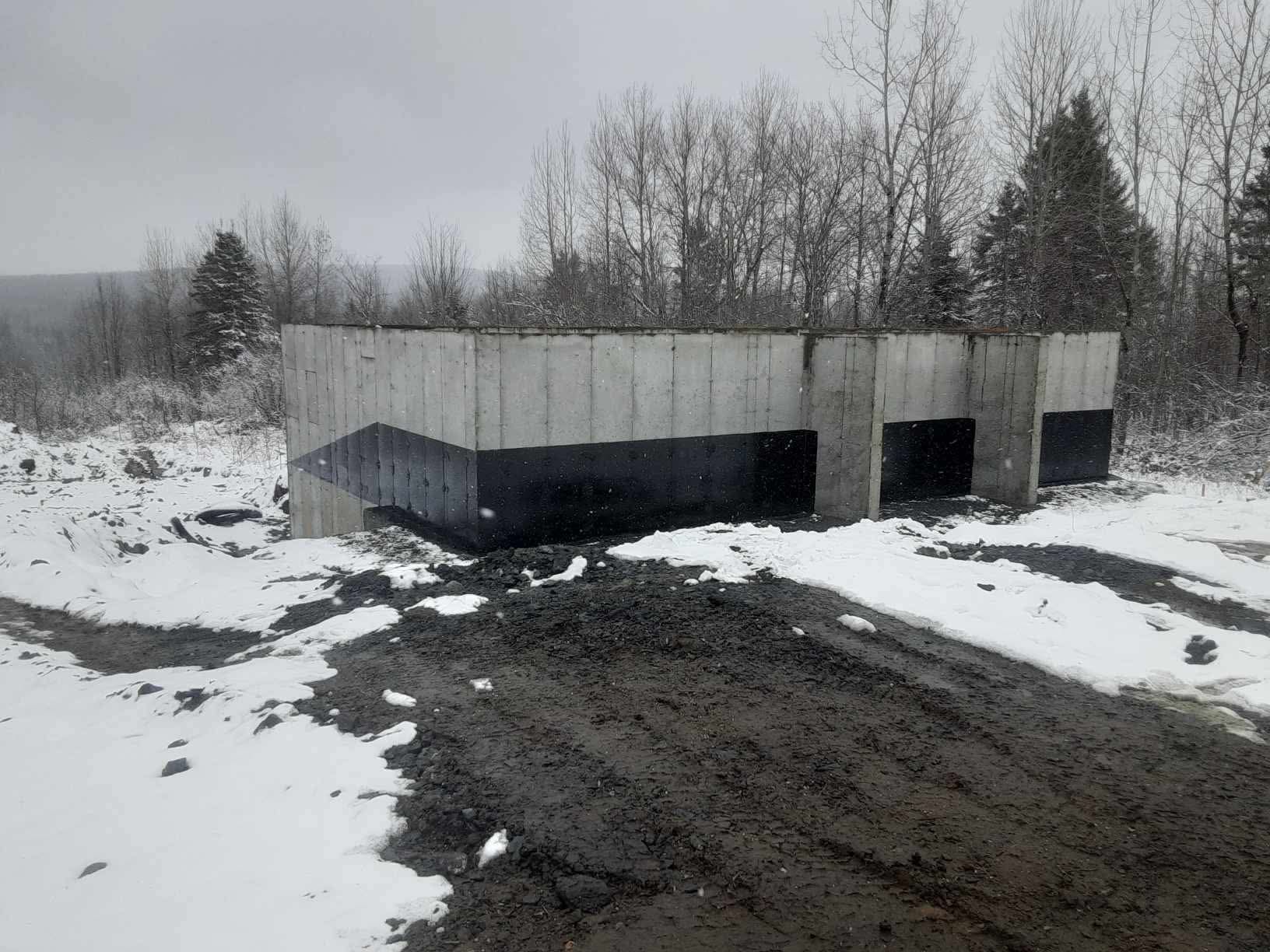 Fondation en béton dans un paysage enneigé, certains murs noirs.