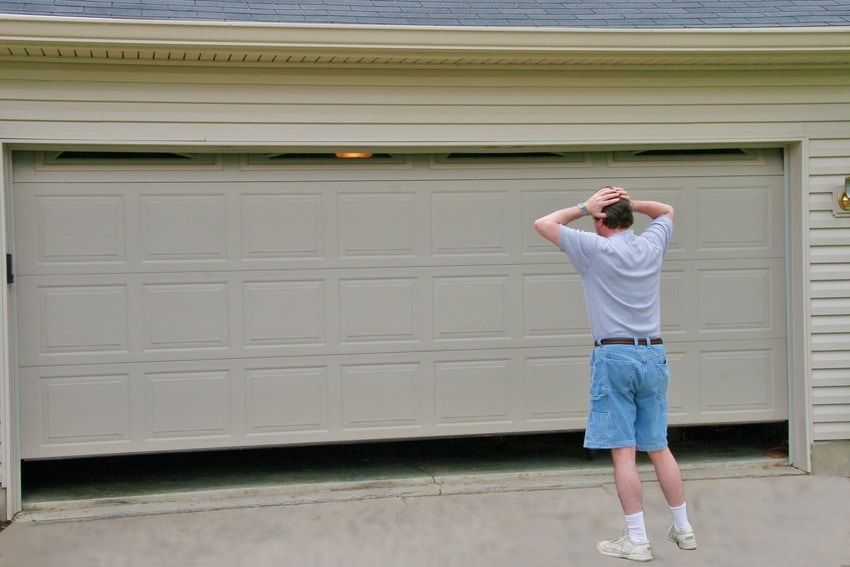 A man is standing in front of a garage door that is open.